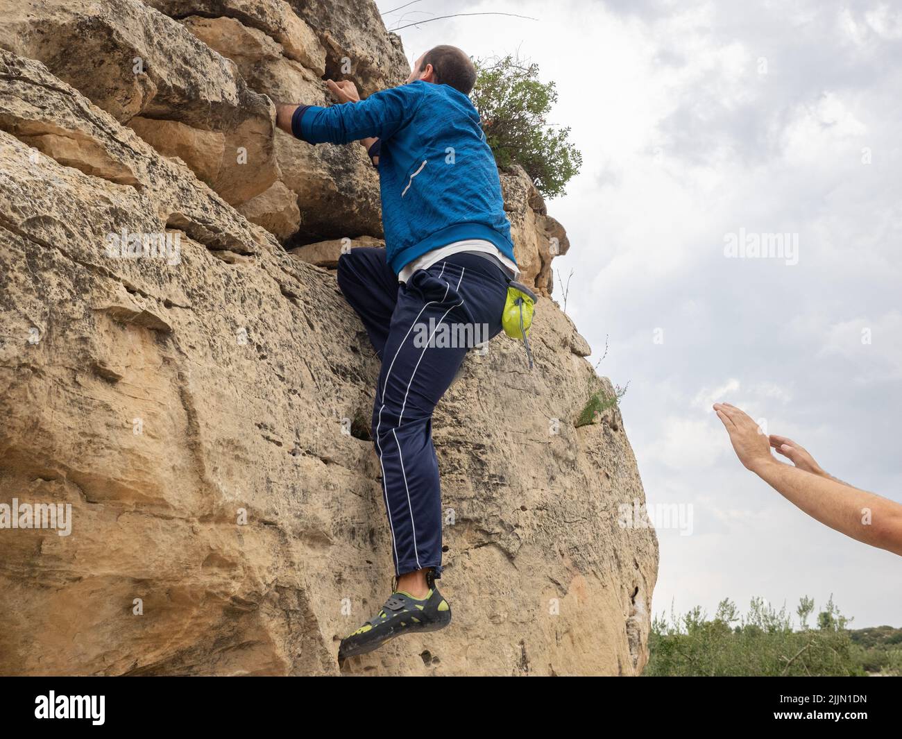 Ein junger Mann, der auf Steinfelsen klettert Stockfoto