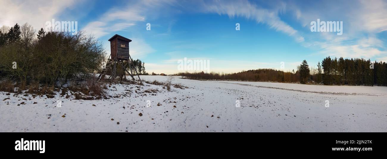 Ein Luftpanorama des schneebedeckten Feldes mit Jagdturm im Hintergrund von Bäumen Stockfoto