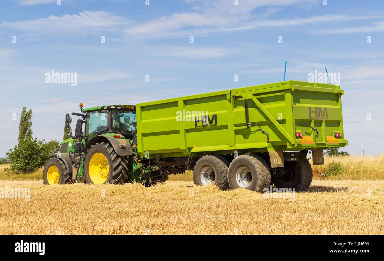 Traktor mit Getreideanhänger auf einem geernteten Feld. VEREINIGTES KÖNIGREICH. August 2022. Stockfoto