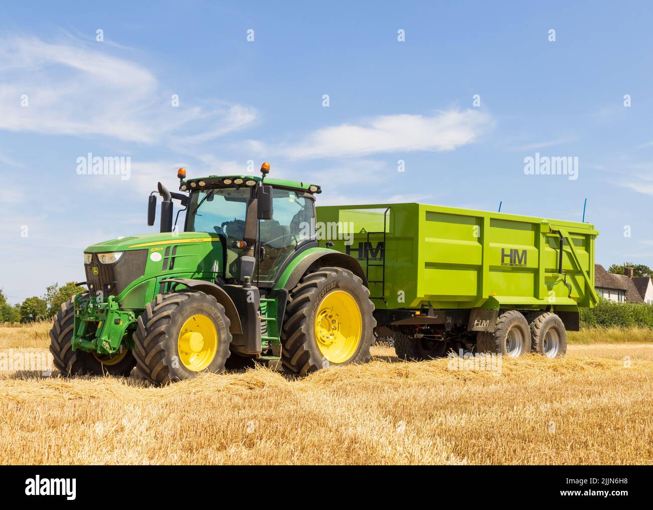 Traktor mit Getreideanhänger auf einem geernteten Feld. VEREINIGTES KÖNIGREICH. August 2022. Stockfoto
