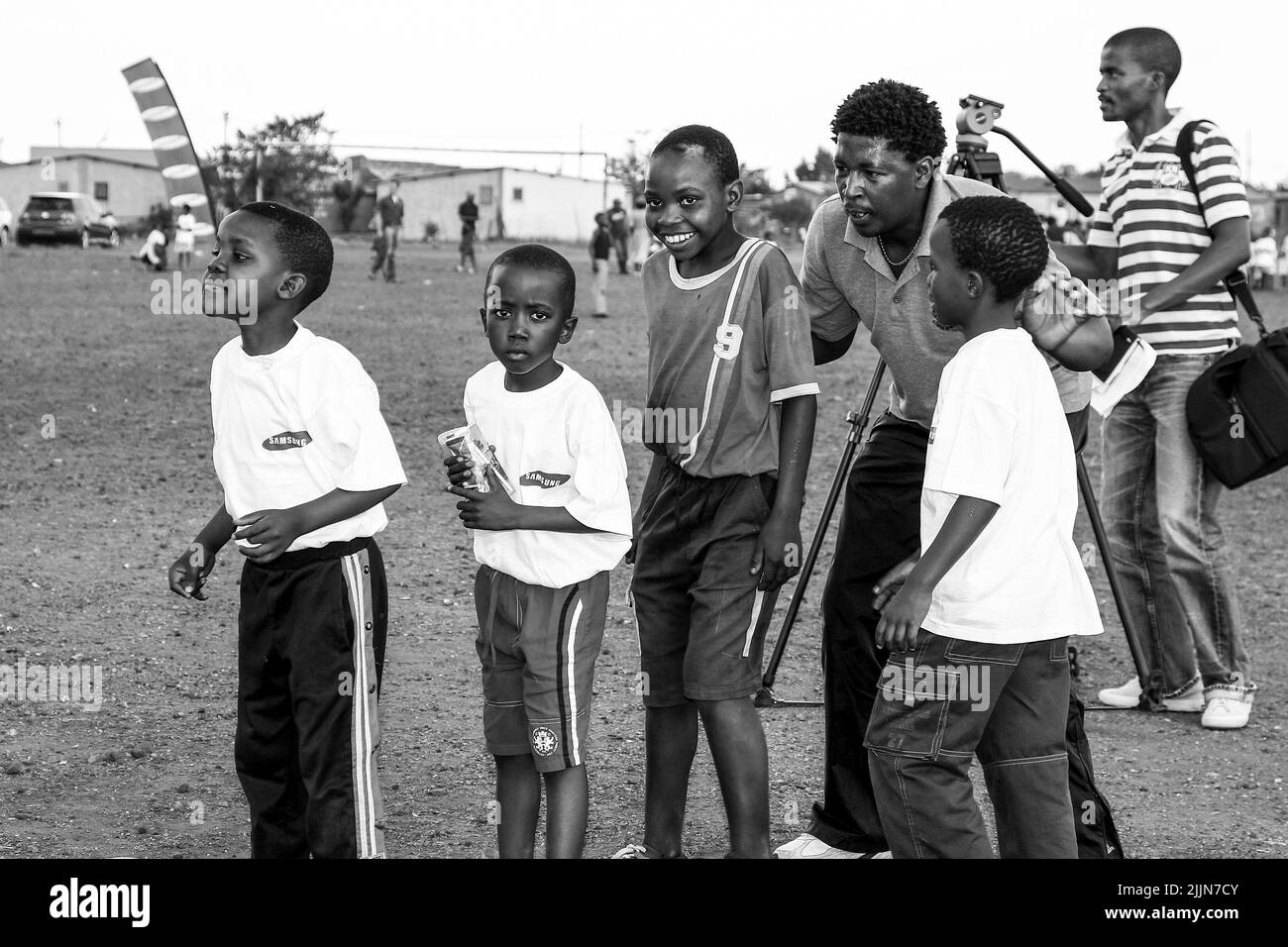 Eine Graustufe afrikanischer Kinder, die auf dem Schulhof in Johannesburg, Südafrika, Fußballaktivitäten durchführen Stockfoto