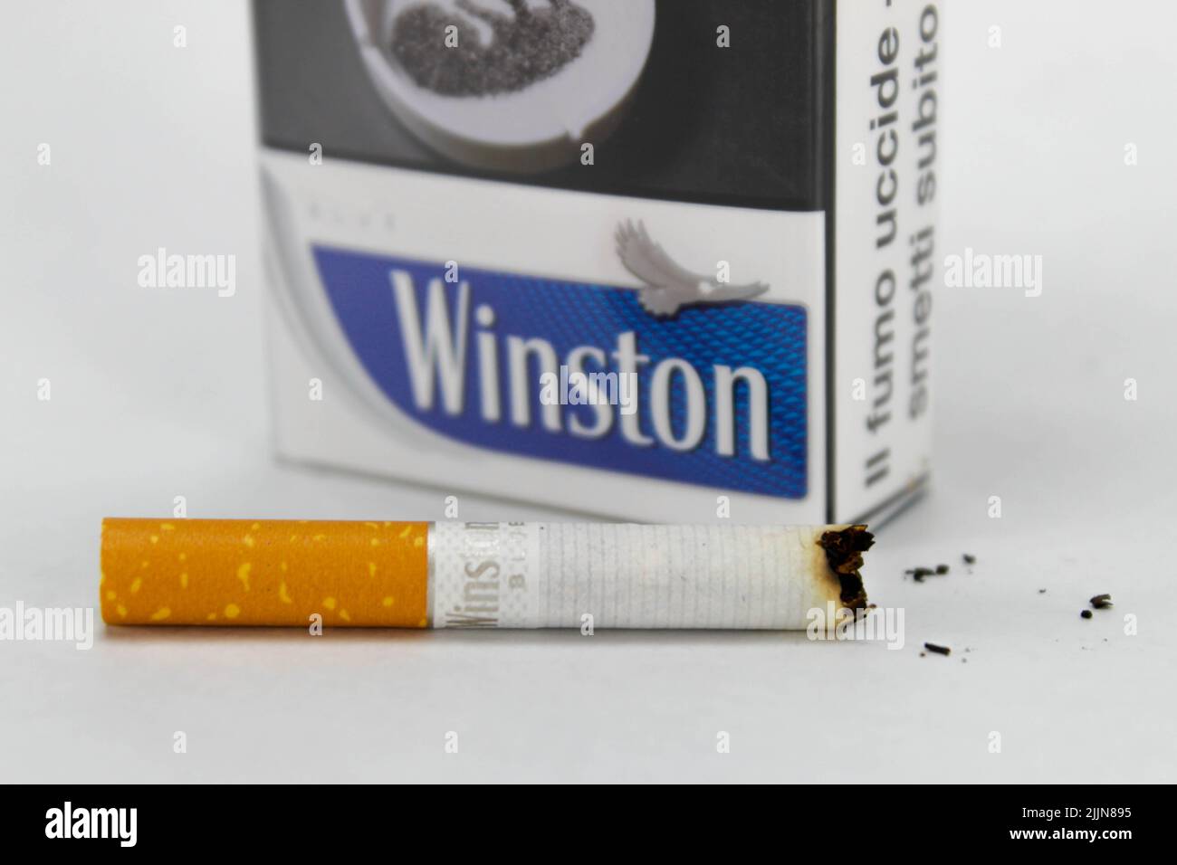 Eine Nahaufnahme einer Packung Winston Zigarette mit einer halb verbrannten Zigarette auf der weißen Oberfläche Stockfoto