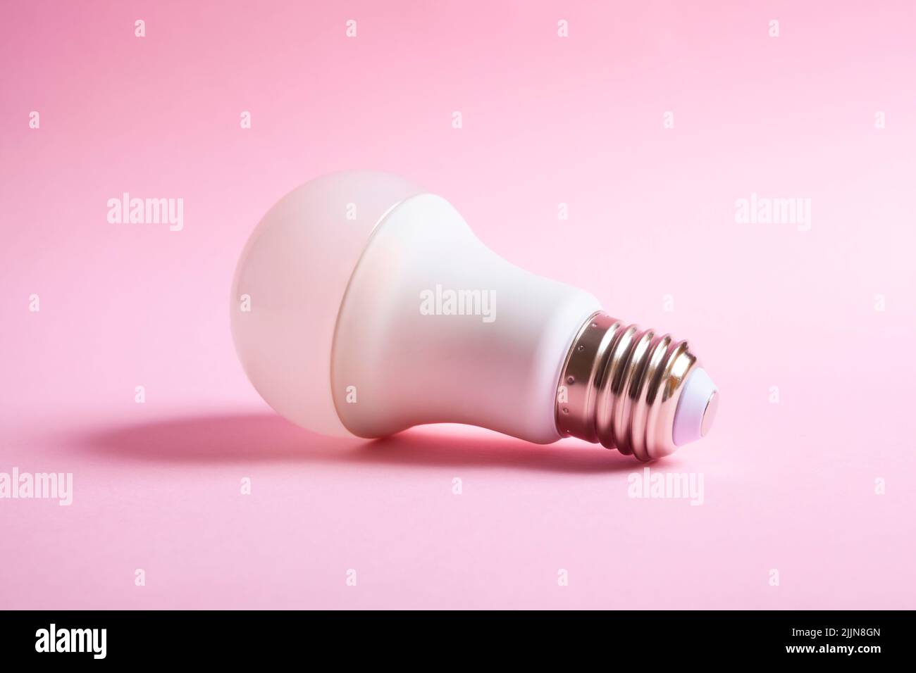 Beleuchtete Glühbirne isoliert auf einem rosa Hintergrund. Ideenkonzept. Stockfoto