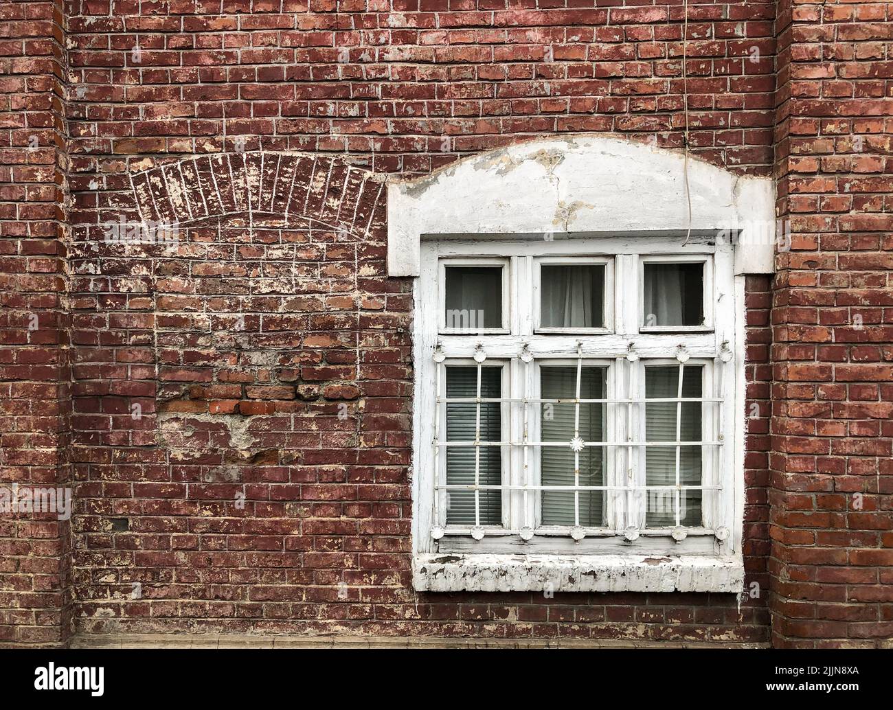 Ein altes weißes Fenster auf einem alten Backsteingebäude Stockfoto