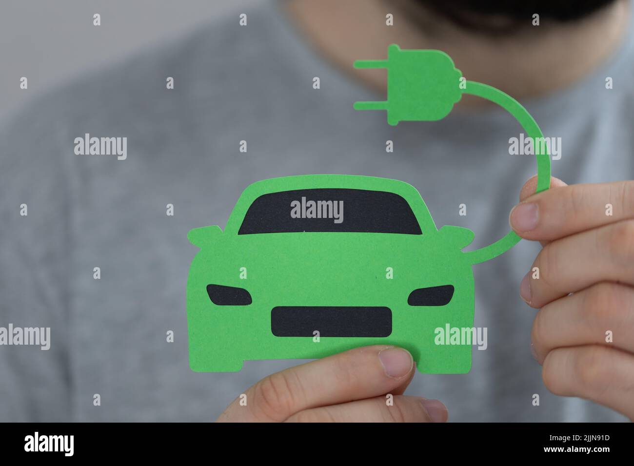 Ein Mann, der ein elektrisches grünes Auto mit Papierausschnitt hält Stockfoto