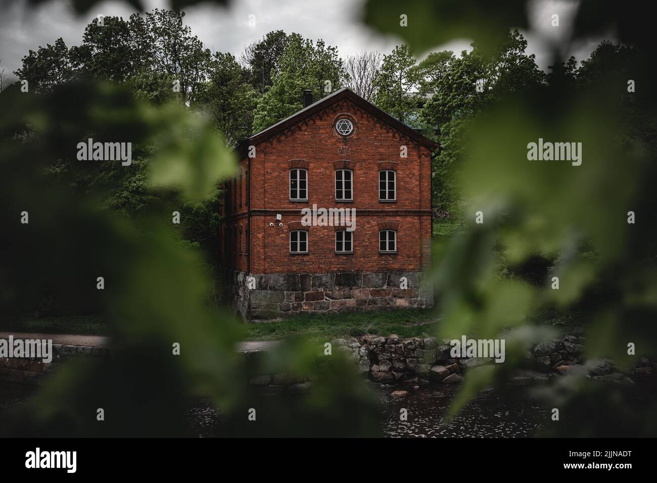 Eine schöne Aufnahme eines roten Backsteinhauses im üppigen Wald Stockfoto
