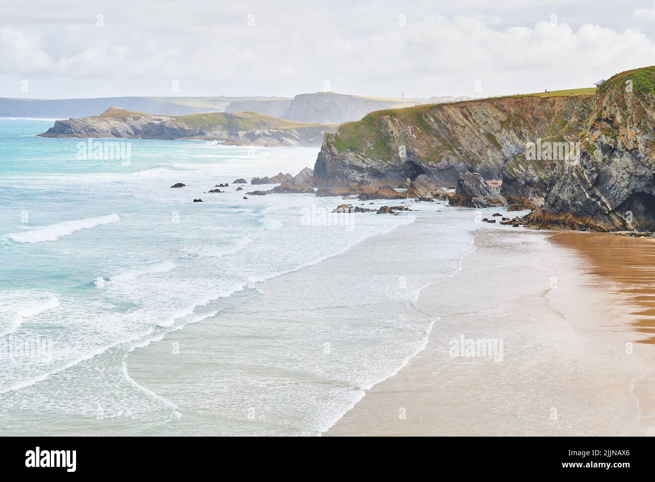 Sanfte Wellen vom atlantischen Ozean brechen an den Klippen und am Strand von Newquay, Cornwall, England. Stockfoto