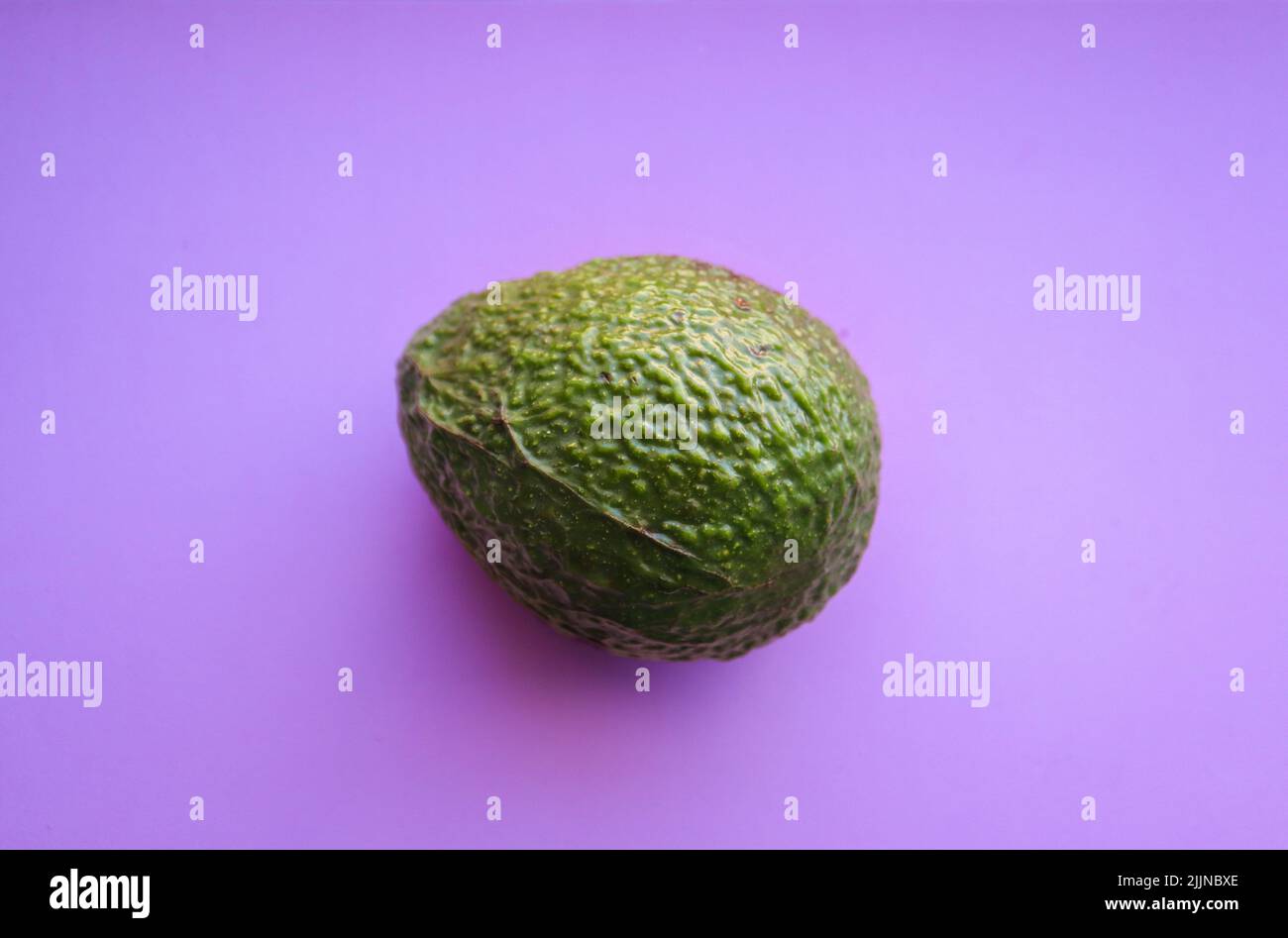 Avocado auf violettem Hintergrund Stockfoto