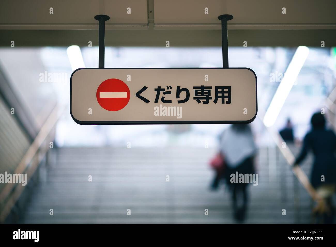 Schild mit der Aufschrift „kudari senmon“ (nur unten) auf Stufen in einem japanischen U-Bahn-System. Stockfoto