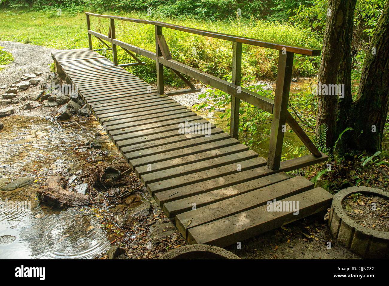 Einfache hölzerne Fußgängerbrücke, um einen Bach an einem Wanderweg in deutschland zu überqueren Stockfoto