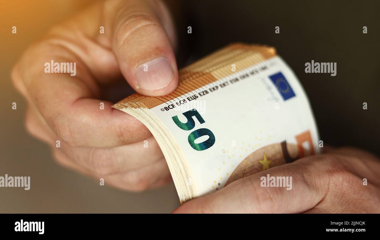 Mann, Der Geld Zählt. Nahaufnahme der männlichen Hände mit einem Stapel von 50-Euro-Banknoten. Geldwechsel in Euro. Bargeldberechnung. Konzept des Gehalts. Stockfoto