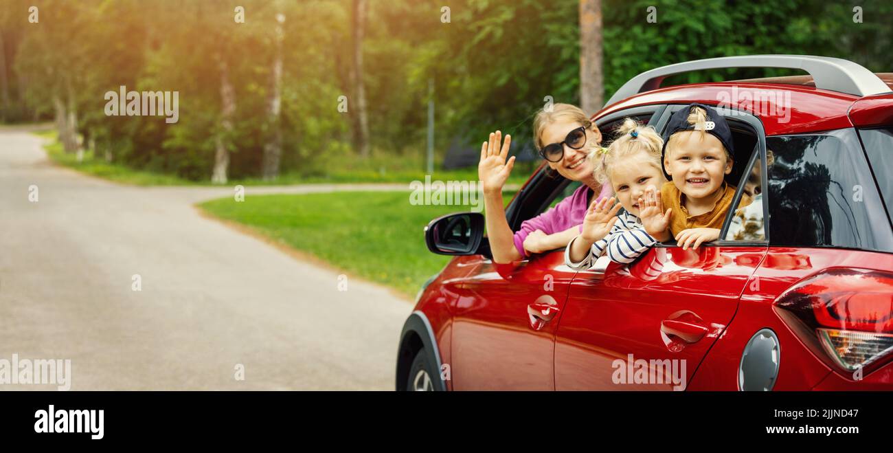 Familienausflug. Mutter mit Kindern winkt aus dem Autofenster. Banner mit Kopierplatz Stockfoto