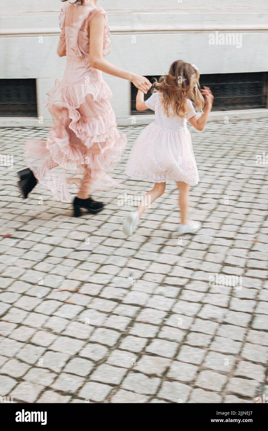 Eine laufende Mutter und Tochter in eleganten Kleidern auf einer Straße Stockfoto