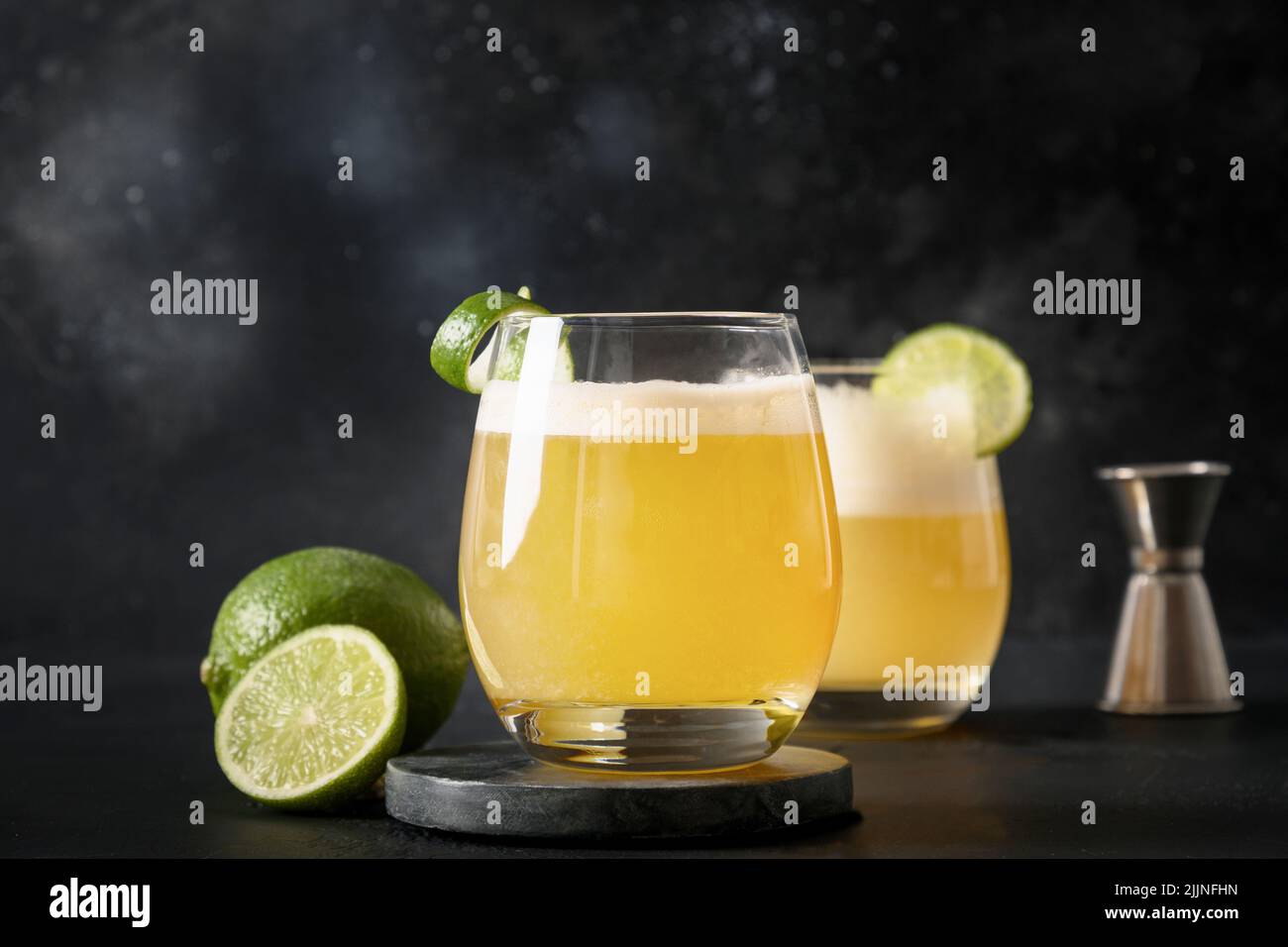 Pisco Sour Cocktail mit Zutaten auf schwarzem Hintergrund. Horizontale Ausrichtung. Hausgemachte Getränke und Aperitif für festliche Party. Nahaufnahme. Stockfoto