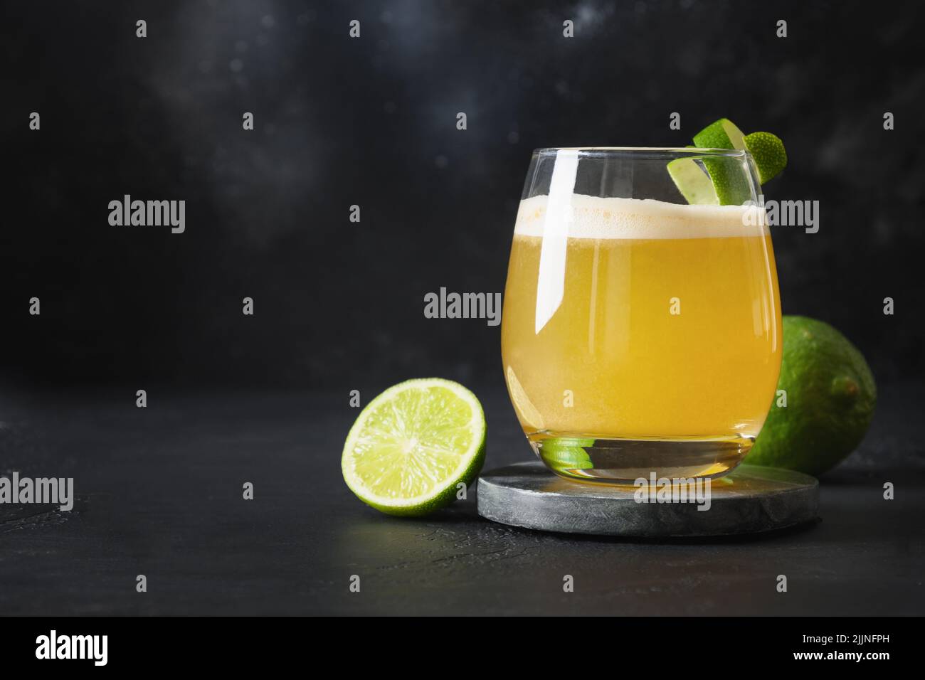 Pisco Sour Cocktail mit Limette auf schwarzem Hintergrund. Horizontale Ausrichtung. Speicherplatz kopieren. Stockfoto