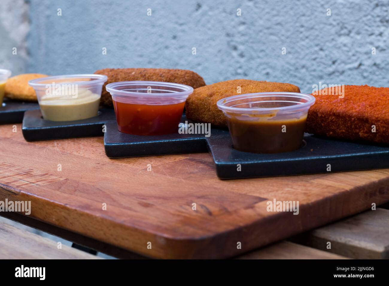 Nahaufnahme verschiedener Nuggets und Saucen auf einem Holzbrett Stockfoto