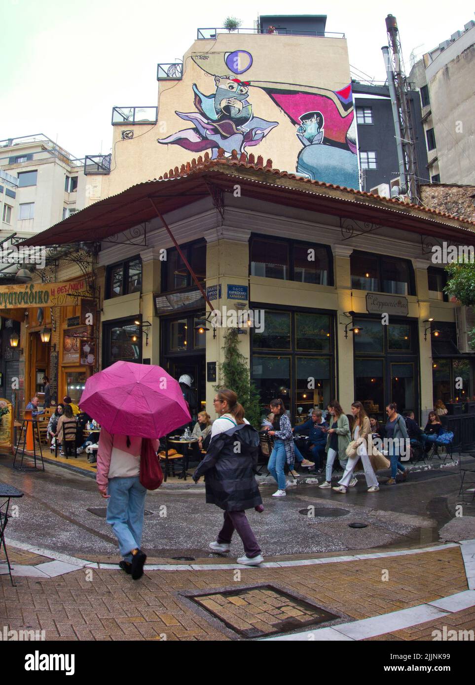 Eine vertikale Aufnahme eines überfüllten Pubs an der Ecke einer Straße im Stadtteil Plaka, Athen Stockfoto