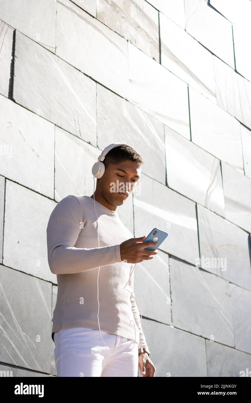 Ein lateinischer Mann, der mit seinem Telefon gerne Musik über Kopfhörer hört Stockfoto