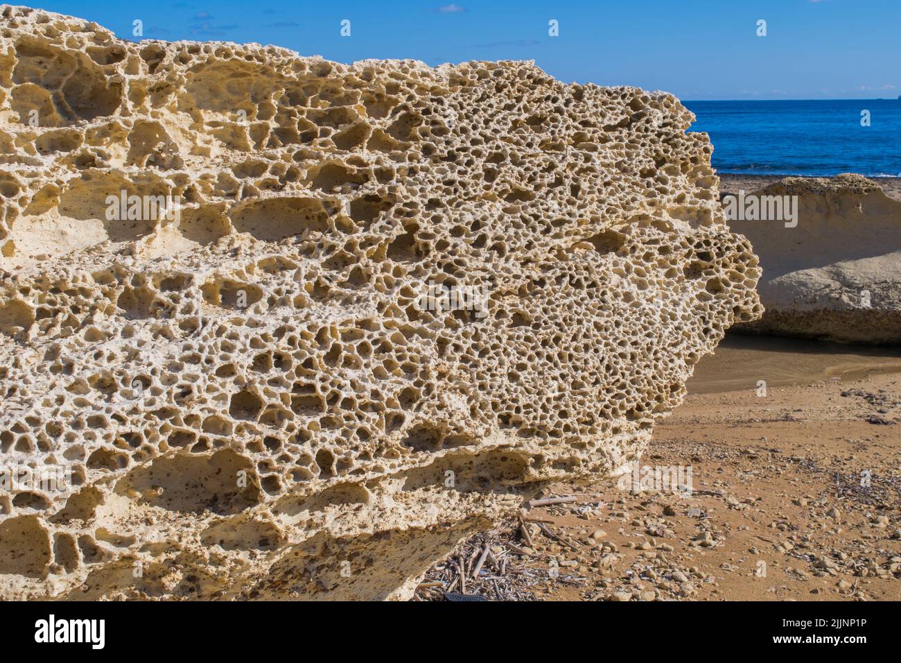 Ein Felsblock aus globigerina Kalkstein nahe der Küste, der an einem sonnigen Tag Anzeichen von Seeverwitterung und Erosion in der maltesischen Landschaft zeigt. Stockfoto