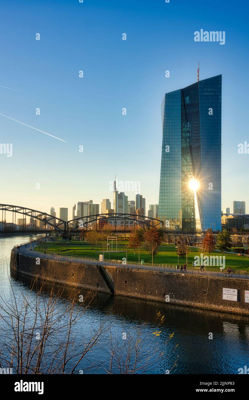 Eine vertikale Aufnahme der Sonne, die vor dem Hintergrund des Himmels durch die Europäische Zentralbank scheint. Stockfoto