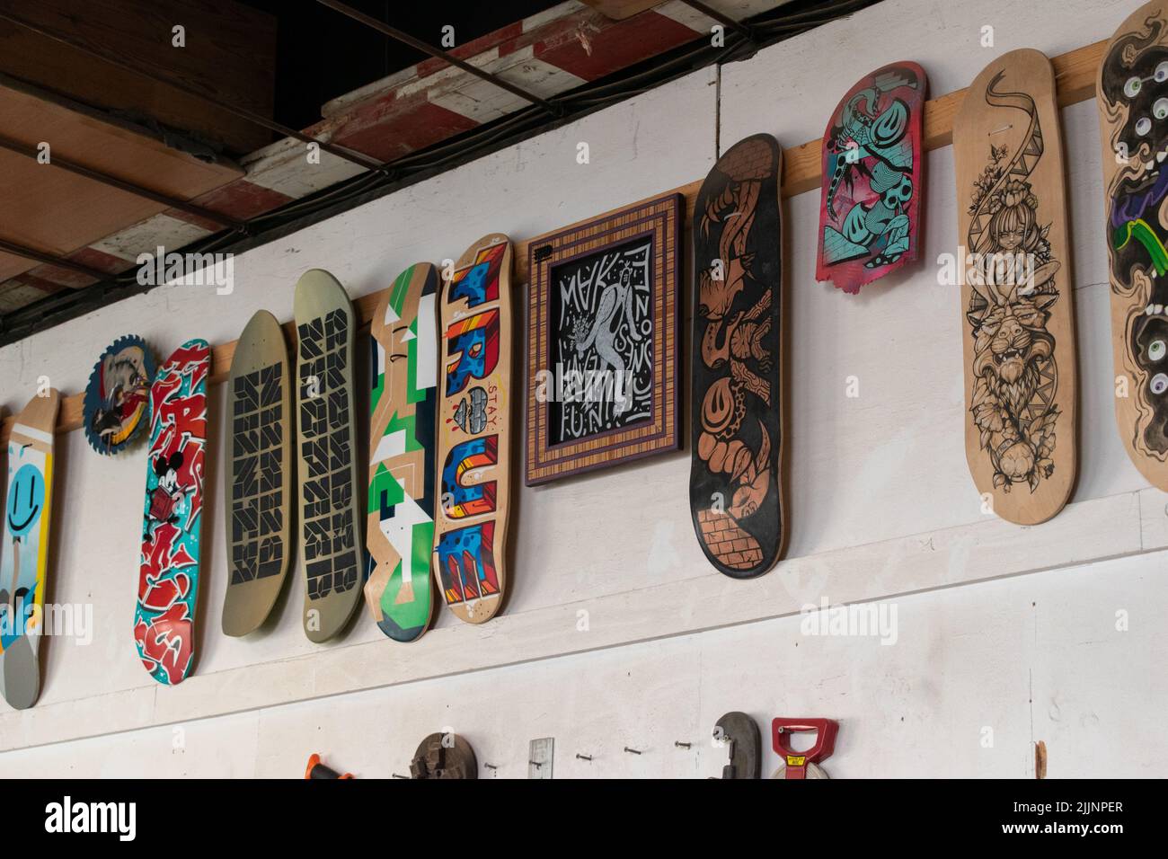 Eine Reihe von Skateboards mit verschiedenen Designs an einer Wand Stockfoto