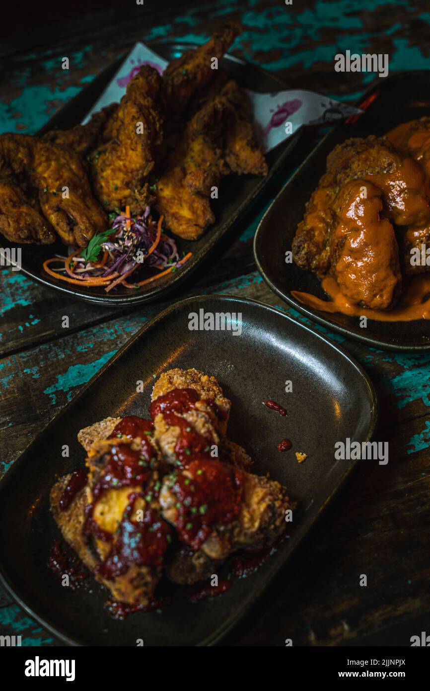 Eine vertikale Aufnahme von Hähnchenflügeln in dunklen, grungigen Restaurants Stockfoto