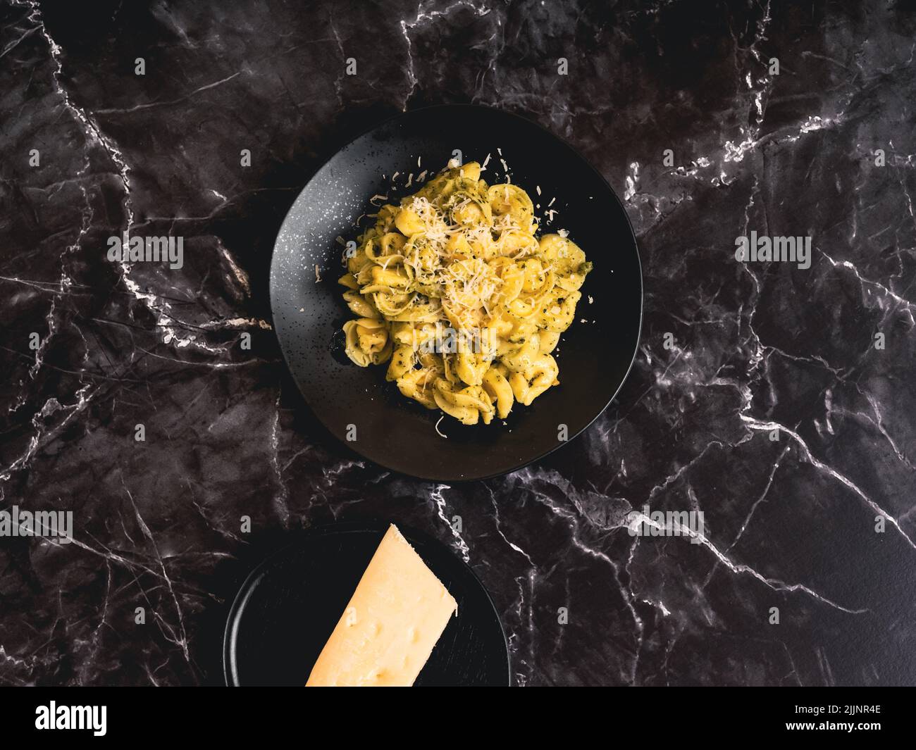 Ein Schuss Tortellini-Pasta mit Parmesan auf schwarzer Marmoroberfläche Stockfoto