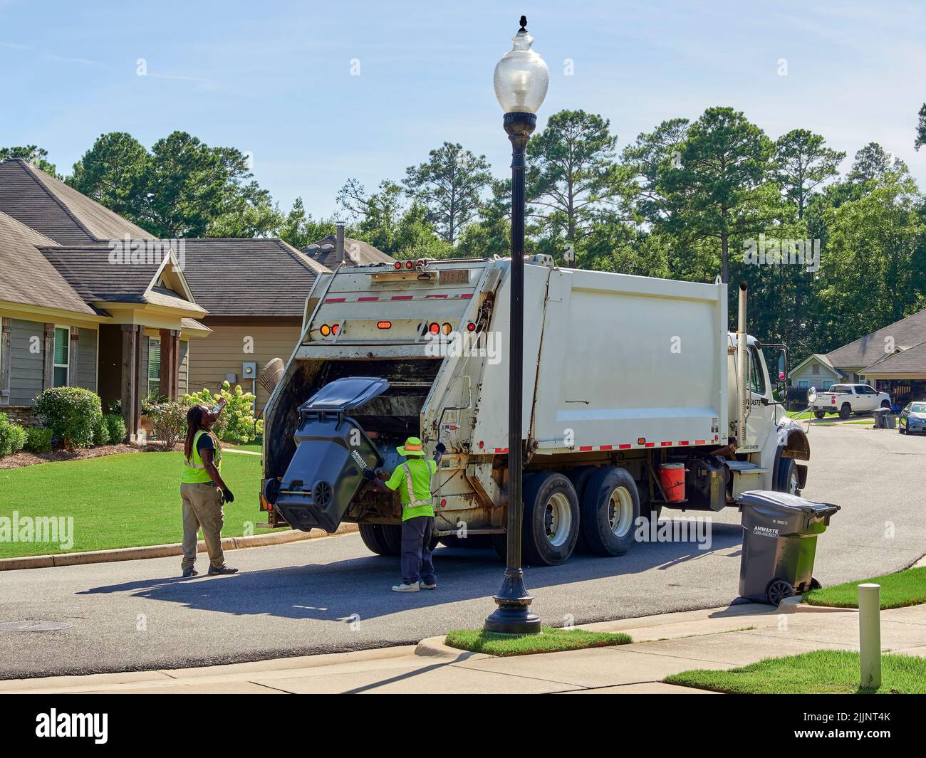 Müllwagen und Müllmänner, die den Müll in einem Wohnviertel in der Pike Road Alabama, USA, abholen. Stockfoto