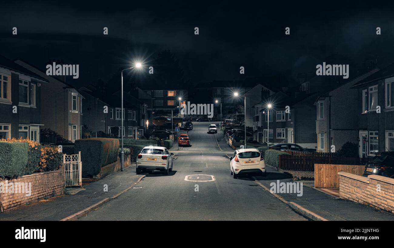 Nachts Blick auf die von Autos und Gebäuden umgebene britische Vorstadtstraße Stockfoto