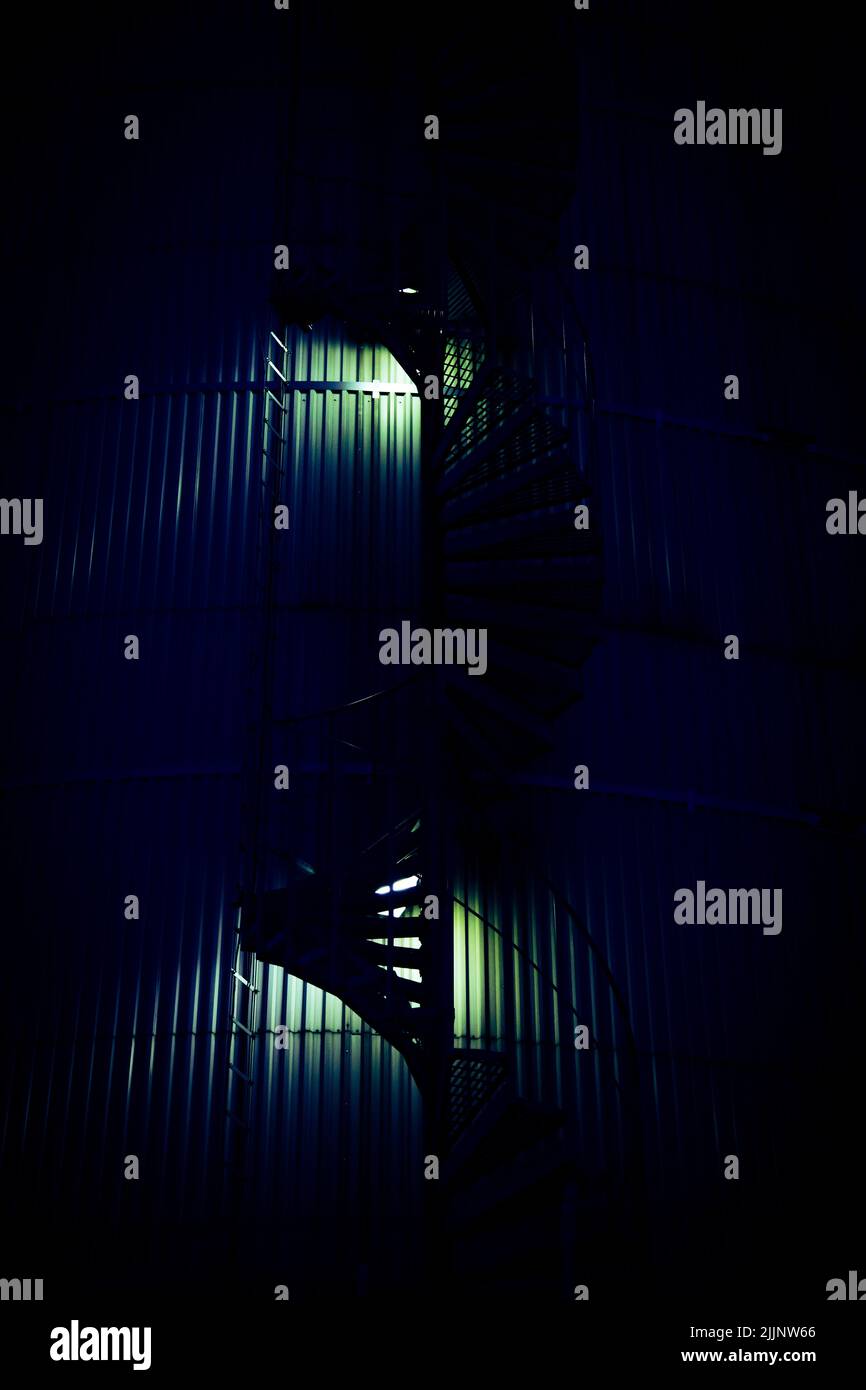 Eine vertikale Aufnahme einer runden Treppe auf einem Industriegebäude spät in der Nacht Stockfoto