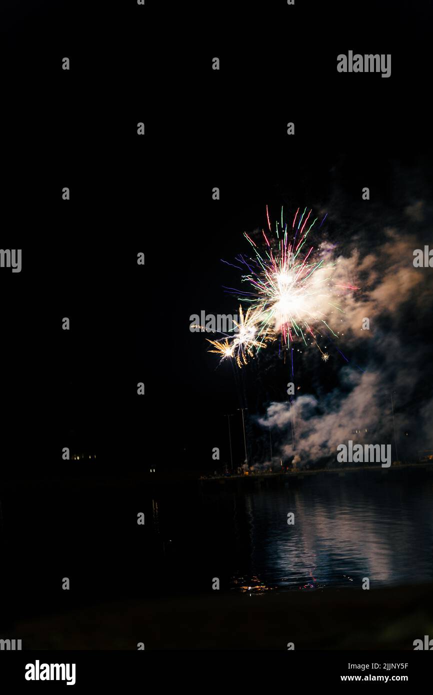 Ein faszinierender Blick auf das Feuerwerk über der Stadt und dem Seeufer spät in der Nacht Stockfoto