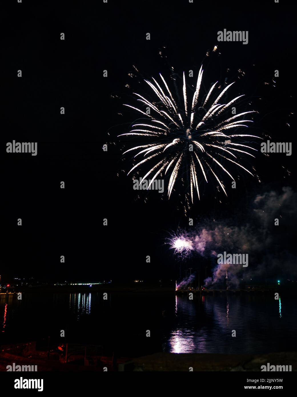 Ein faszinierender Blick auf das Feuerwerk über der Stadt und dem Seeufer spät in der Nacht Stockfoto