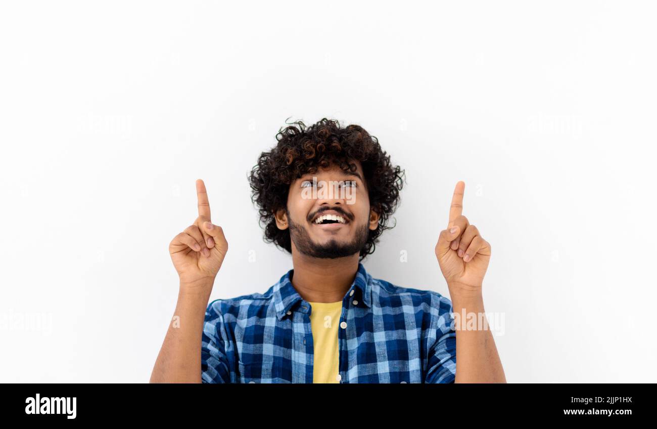 Junger asiatischer Mann lächelt mit dem Finger nach oben und zeigt auf weißem Hintergrund mit Kopierraum, lächelt freundlich Stockfoto