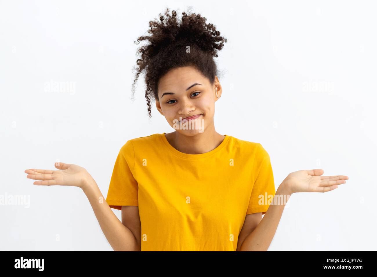 Das Porträt einer jungen, unglücklichen Afroamerikanerin mit lockigen Haaren hebt verzweifelt ihre Hände auf weißem Hintergrund Stockfoto