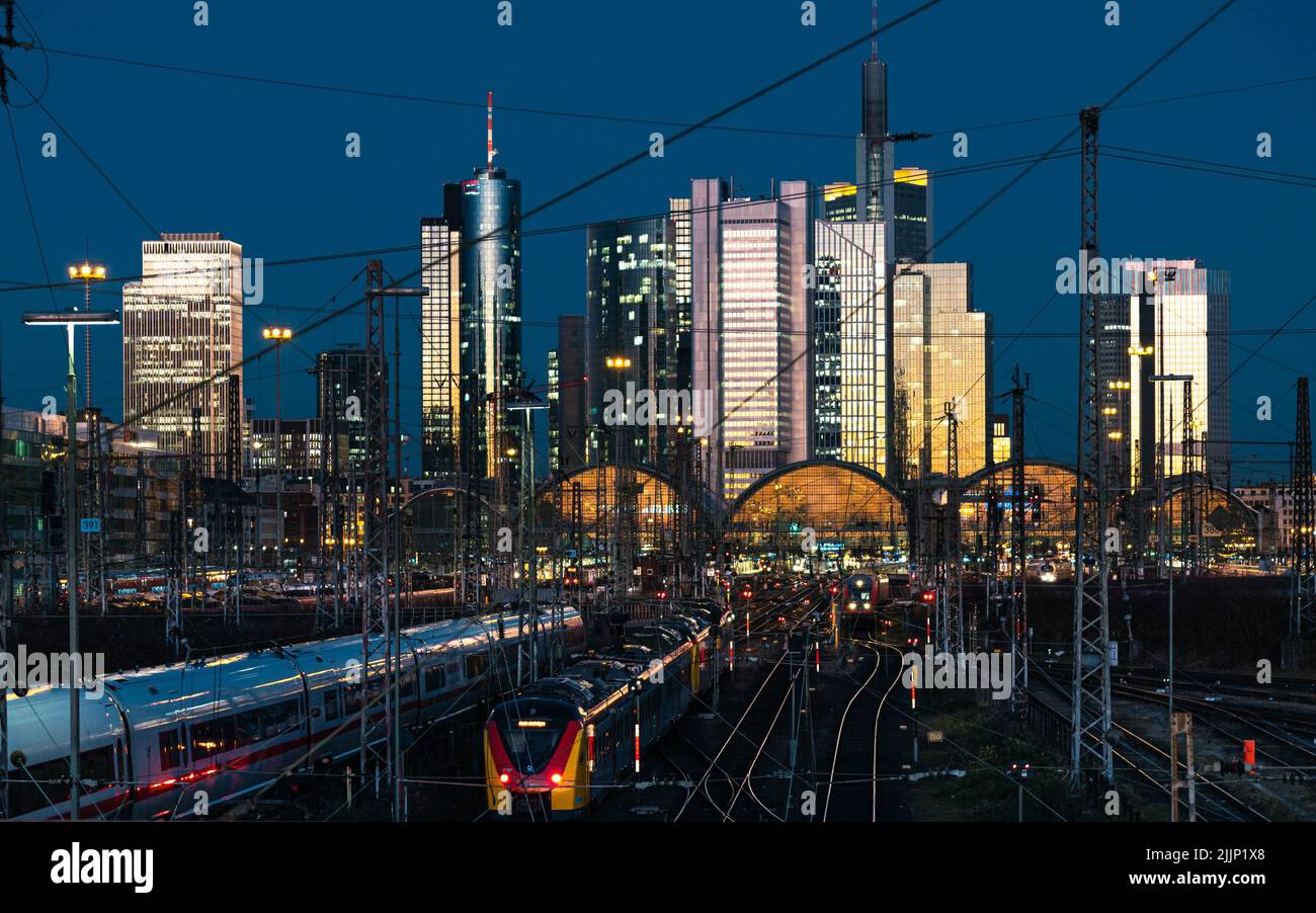 Die Züge fahren abends mit der beleuchteten Skyline vom Frankfurter Hauptbahnhof ab und fahren dort ein Stockfoto