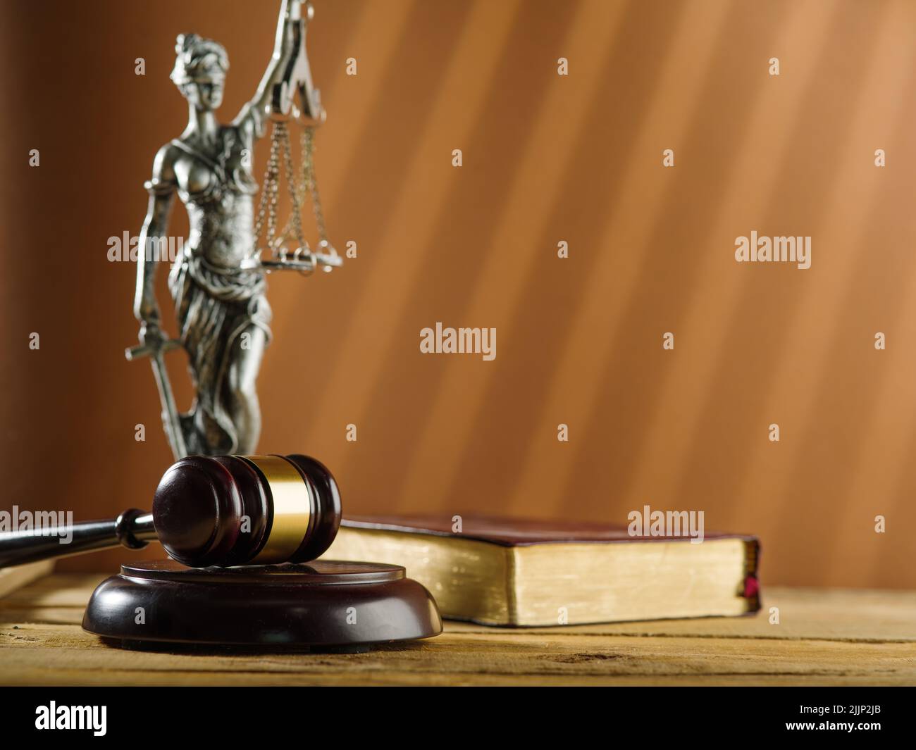 Statuette der Göttin der Gerechtigkeit - Themis, ein hölzerner Gavel eines Richters und ein Buch auf beigem Hintergrund. Symbole eines ehrlichen fairen Prozesses. Constitutio Stockfoto
