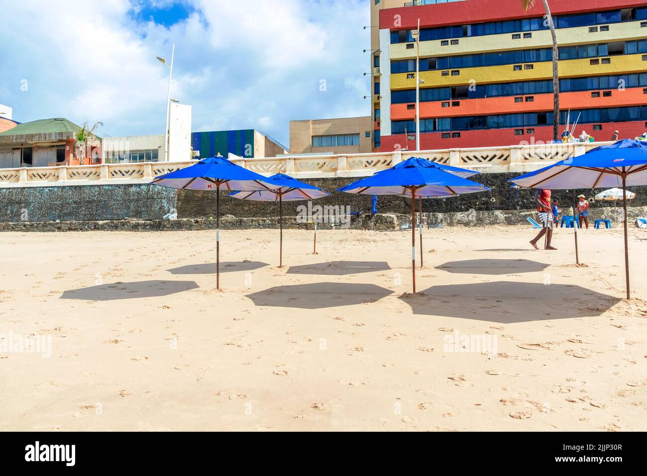 Eine Reihe von Sonnenschirmen mit Schatten auf Sand am Strand Farol da Barra in Salvador, Bahia, Brasilien. Stockfoto