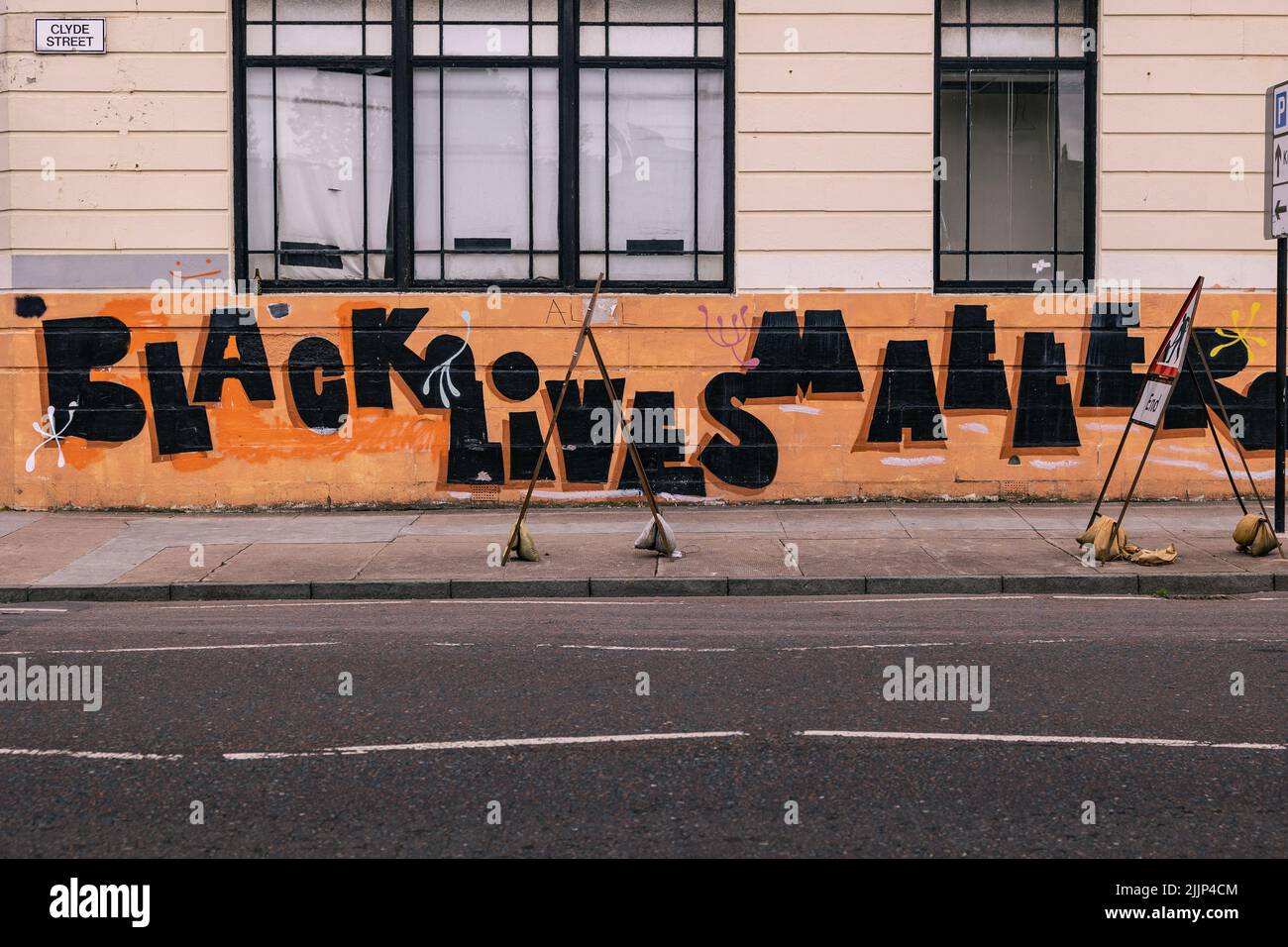 Der Text „Black Lives Matter“, geschrieben auf einer orangefarbenen Wand, Glasgow, Vereinigtes Königreich Stockfoto