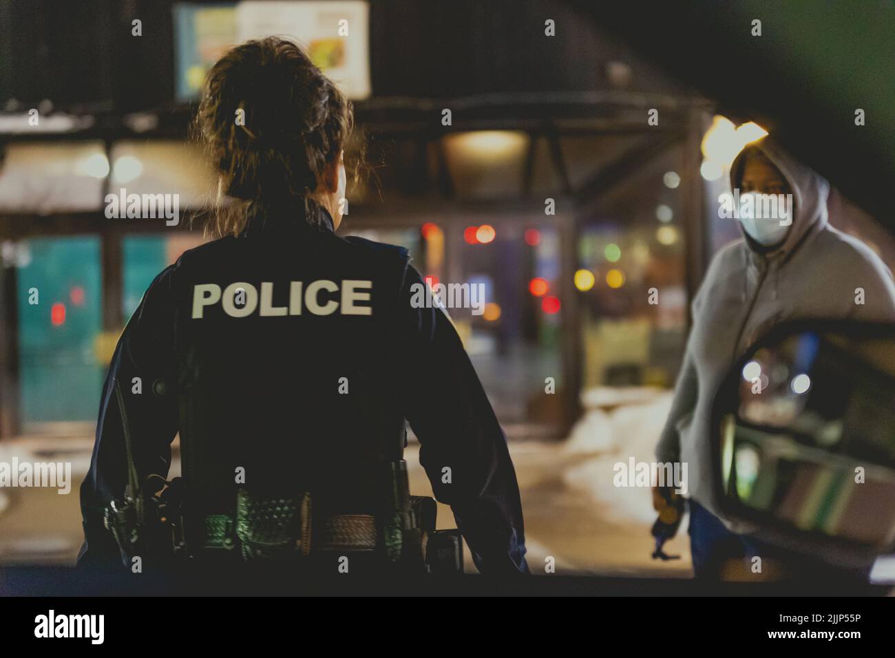 Eine Polizistin, die sich einem Zeugen einer örtlichen Störung nähert, ruft nachts auf der Straße an Stockfoto