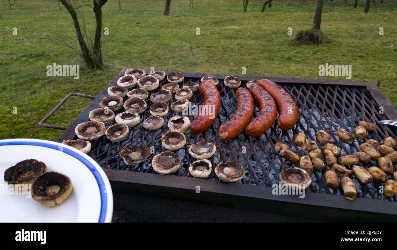 Eine Nahaufnahme eines Grills mit Würsten und Pilzen im Hinterhof Stockfoto