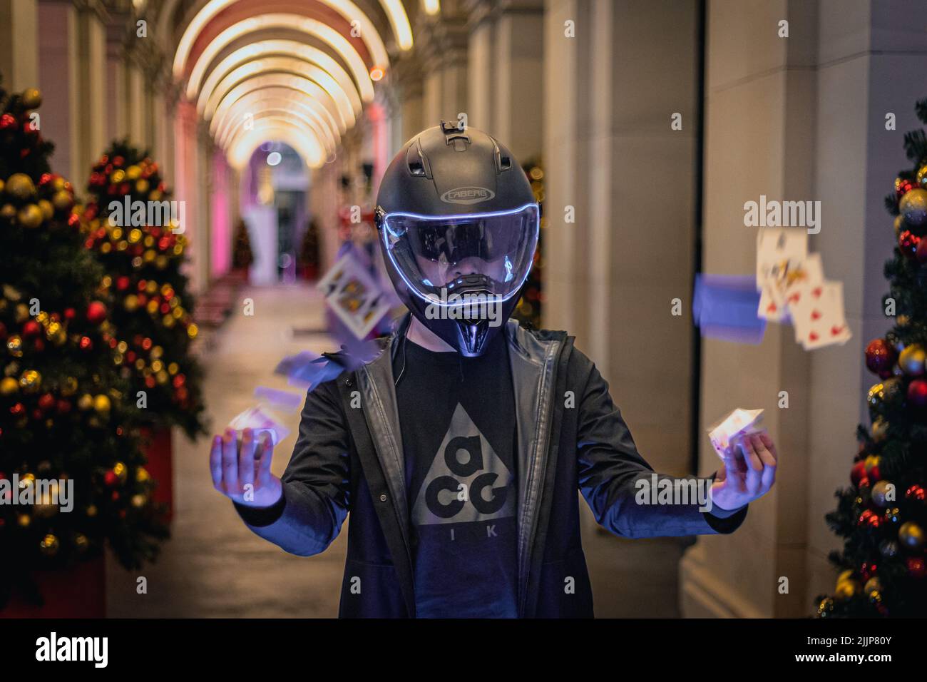 Eine Selektion eines Mannes mit einem Helm, der in einem mit Weihnachtsbäumen geschmückten Korridor mit Karten spielt Stockfoto