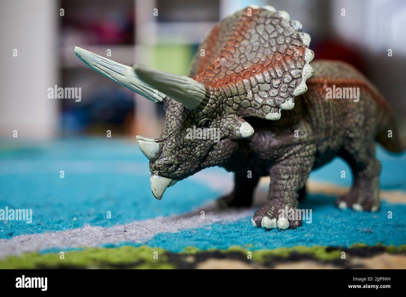 Eine Nahaufnahme eines Triceratops Dinosaurier-Spielzeugs auf einem blauen Teppich Stockfoto