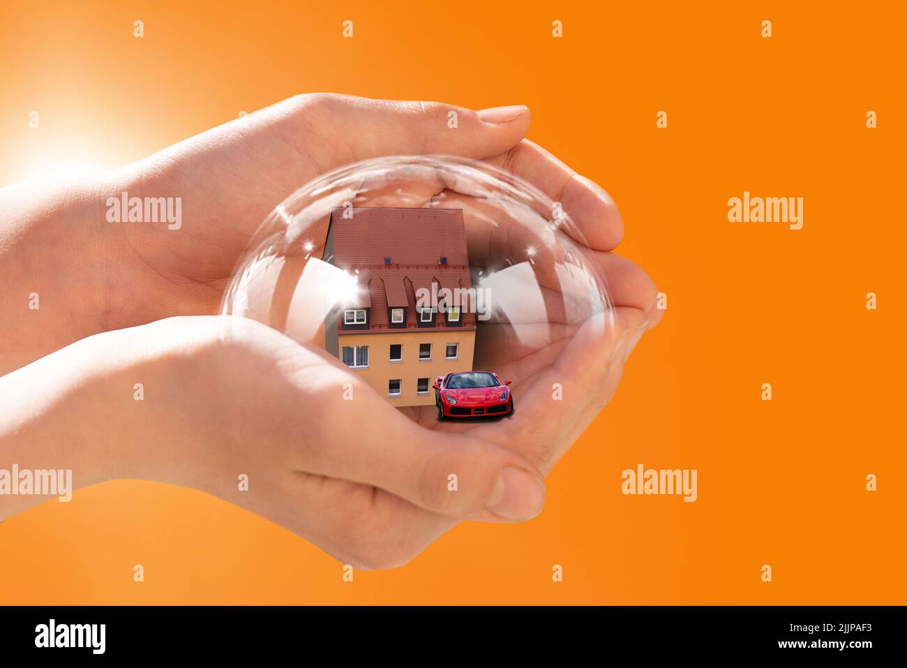 Die Hände einer Person, die ein rotes Auto mit 3D Rendering und ein Haus in einer Sicherheitsblase auf einem orangefarbenen Hintergrund hält - das Konzept der Versicherung Stockfoto Die Hände einer Person, die ein rotes Auto mit 3D Rendering und ein Haus in einer Sicherheitsblase auf einem orangefarbenen Hintergrund hält - das Konzept der Versicherung Stockfoto