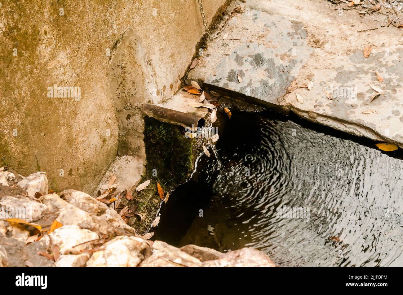 Sauberes, klares Wasser, das aus einem traditionellen, mit Steinen ausgekleideten Metallauslauf oder -Rohr im Wald in Spanien fließt. Stockfoto