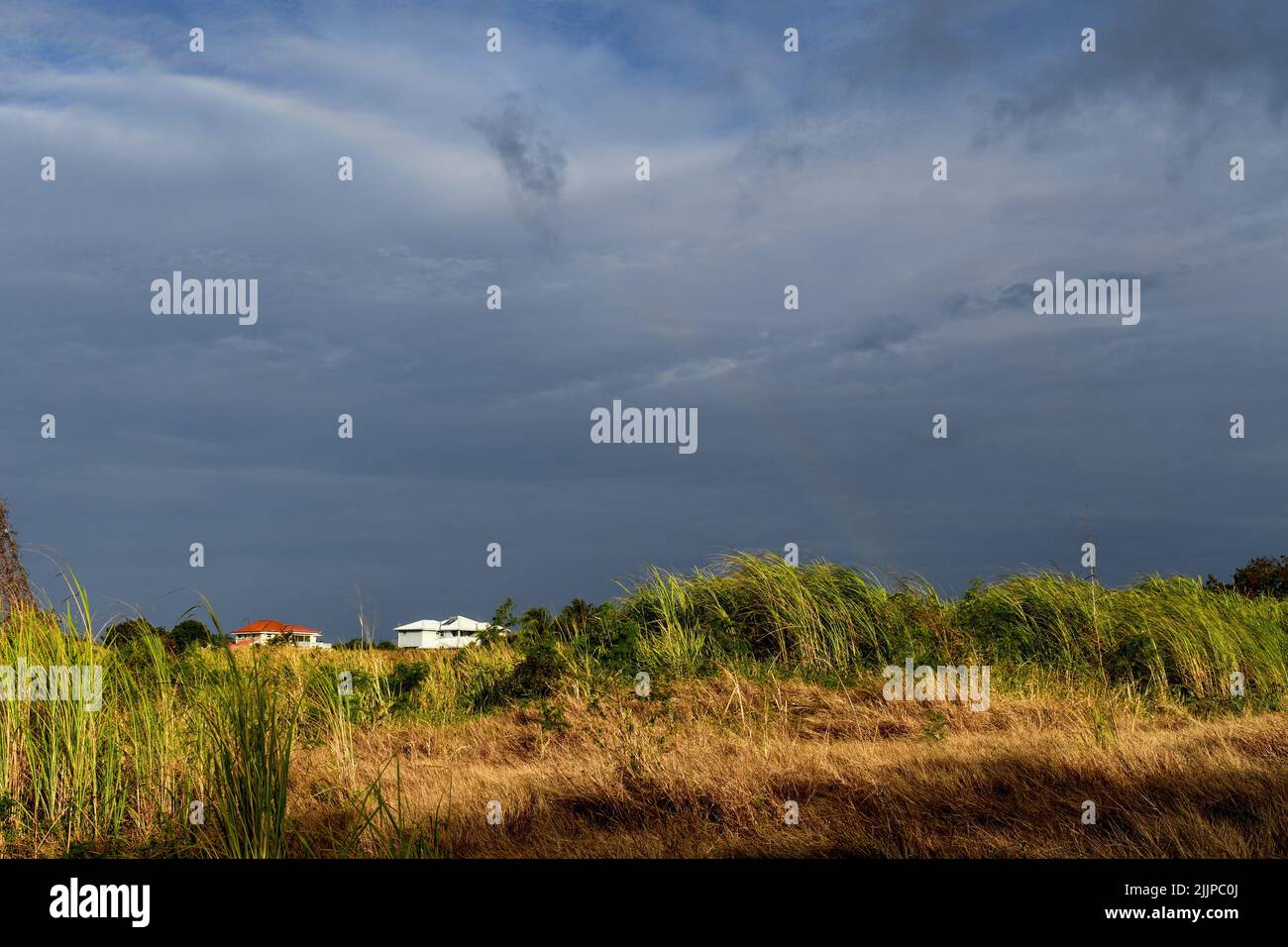 Panoramaaufnahme eines stürmischen Himmels, der durch einen Regenbogen schneidet Stockfoto