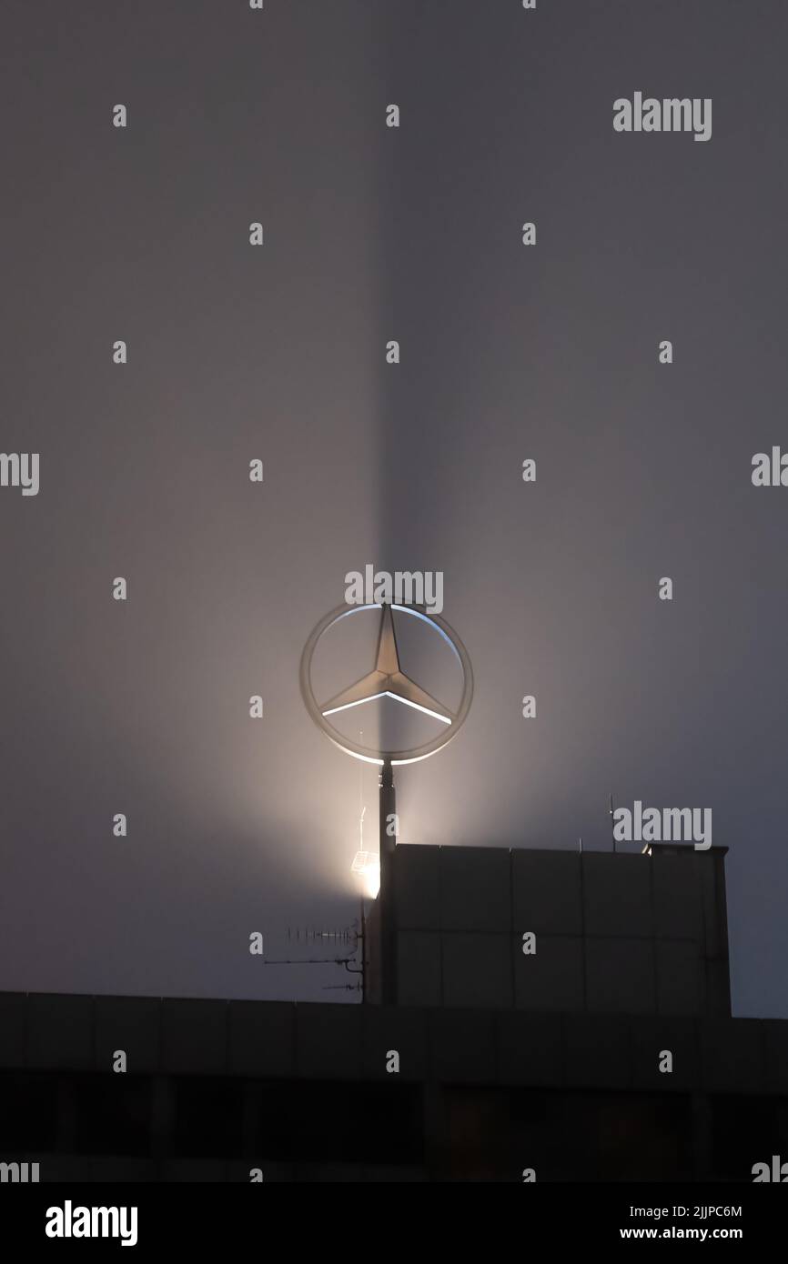 Ein hintergrundbeleuchtetes Mercedes-Benz-Emblem bei Nacht Stockfoto