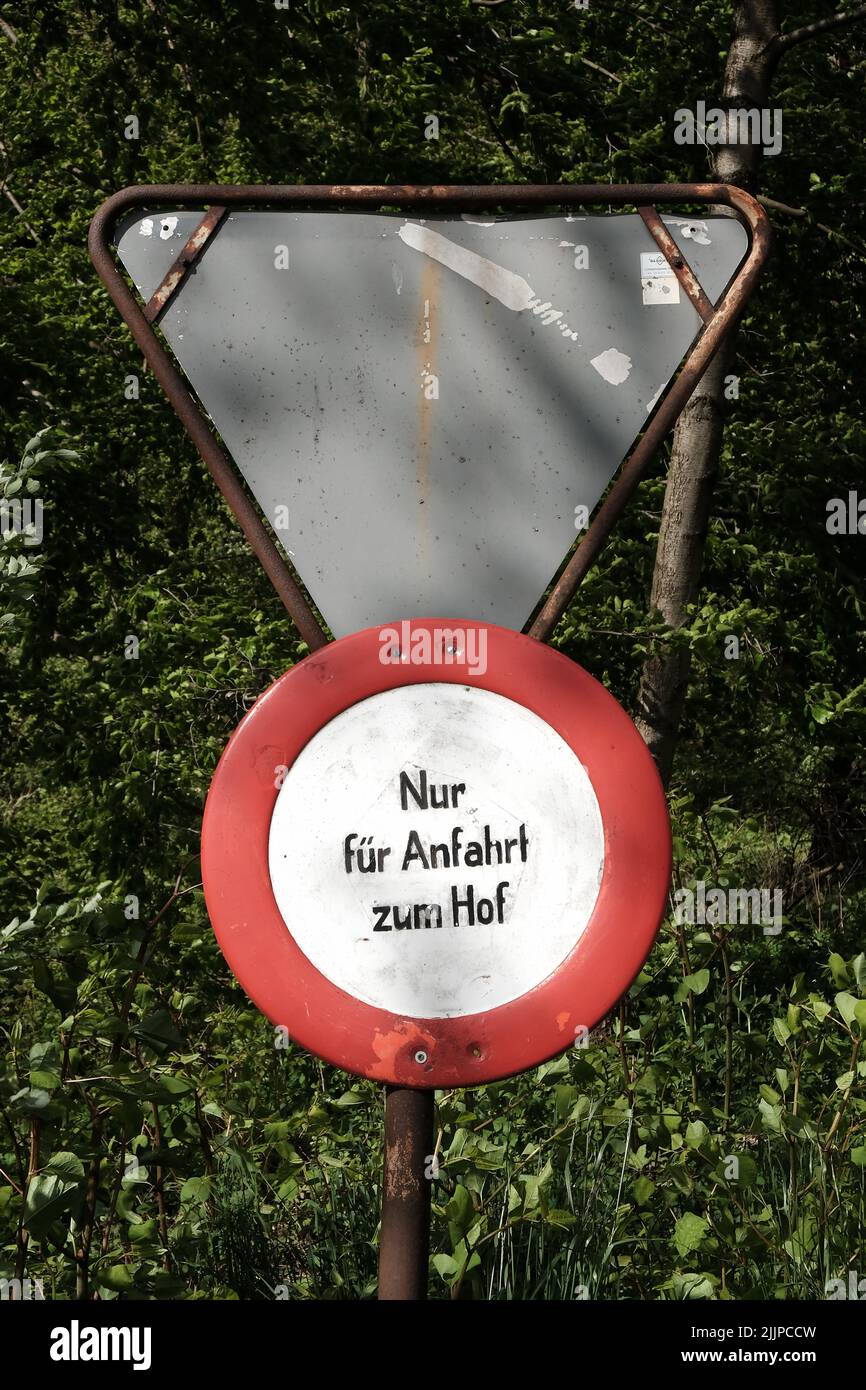 Eine vertikale Aufnahme eines runden rot-weißen Schildes mit dem Text 'nur fur Hinweis zum Hof' gegen die Blätter eines Baumes Stockfoto