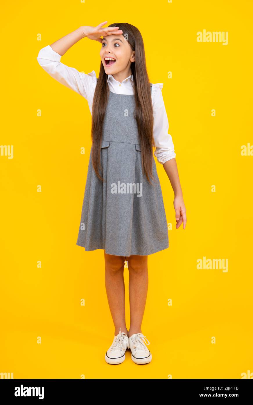 Schuluniform. In voller Länge Foto von brünett teen Mädchen tragen Freizeitkleidung auf gelbem Hintergrund isoliert. Stockfoto
