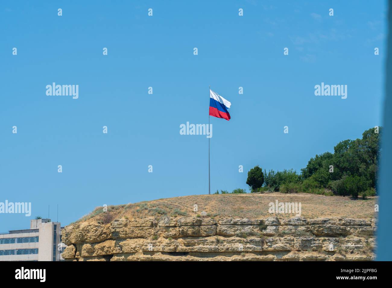 Die russische Flagge winkt am vereinzelten Himmelsweg und stutzt blaues Regierungsemblem, von der Unabhängigkeit der Wirtschaft und dem symbolischen russischen politischen Gefüge Stockfoto