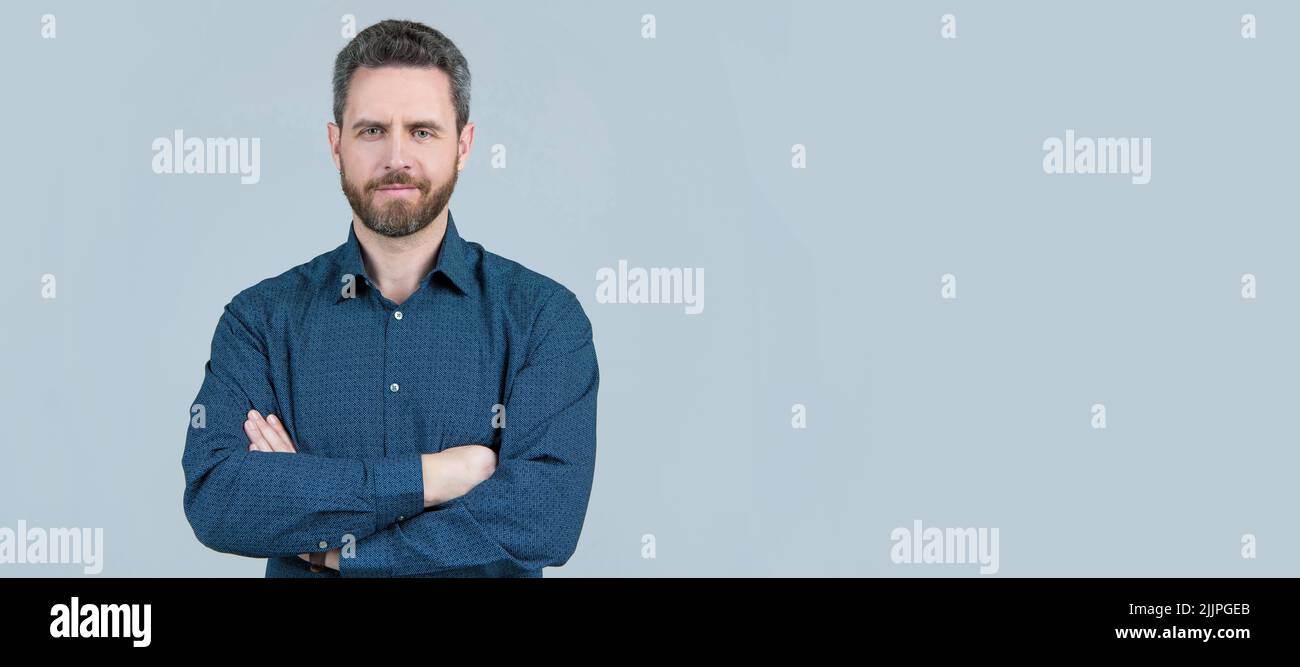Selbstbewusster Mann trägt legeres Hemd mit gekreuzten Armen auf grauem Hintergrund, informelle Kleidung, Kopierraum. Mann Gesicht Porträt, Banner mit Copyspace. Stockfoto